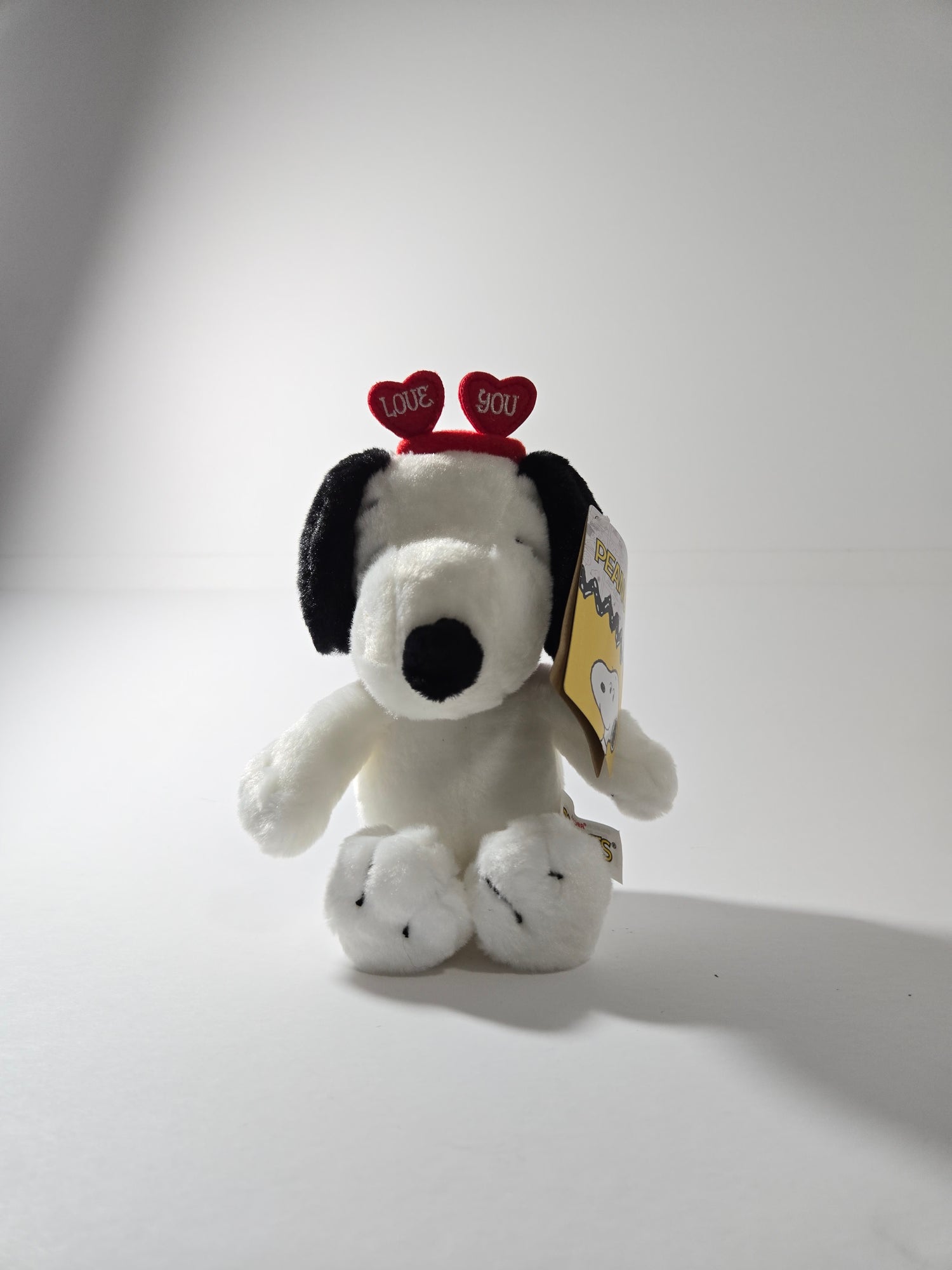 Snoopy plush toy sitting upright with classic black and white features – Peanuts stuffed animal